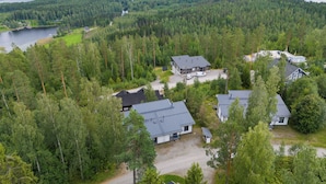 A residential area with multiple houses surrounded by dense forest and a large body of water in the background. - Spacious 2BR Cabin at Riihivuori Peak (Muurame)