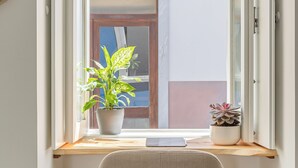 Finestra amb una planta en test i una cadira dins una habitació.