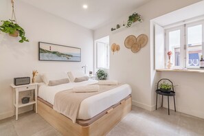 Ein ordentlich eingerichtetes Schlafzimmer mit Bett, Nachttischen, einem Fenster mit Vorhängen und Wanddekorationen.