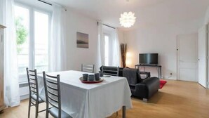 A dining area with a table set for four, a sofa, and a TV stand.