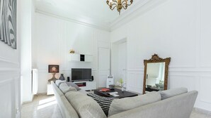 A modern living room with a sofa, TV, and a decorative mirror.