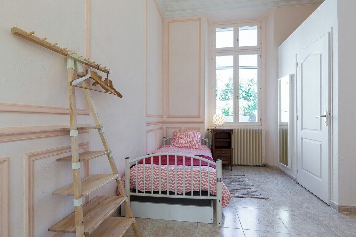 Une chambre à coucher avec un lit, une échelle en bois, un radiateur et une fenêtre.