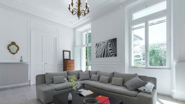 A modern living room with a grey sectional sofa, a black coffee table, and a zebra print artwork on the wall.