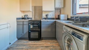 Una cocina compacta con estufa, horno, microondas y lavadora.