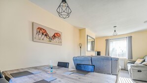 Una sala moderna con una gran mesa de comedor, sofás y un cuadro de perros en la pared.