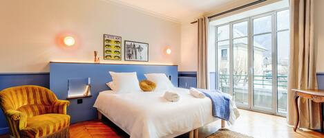 A bedroom with a bed, a chair, a window, and a wall-mounted shelf.