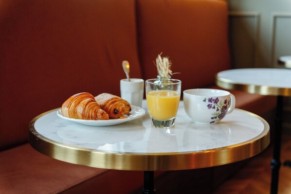 A breakfast setting with croissants, orange juice, and a floral cup on a round table. - Le Falcoz (Saint-Jean-de-Maurienne)