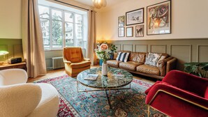Ein Wohnzimmer mit einer Couch, einem Sessel und einem Couchtisch mit Blumen in einer Vase.