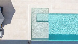 Ein Pool auf dem Dach mit klarem Wasser, einer Glaskonstruktion und einer Steinmauer.