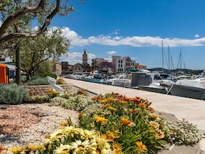 A marina with boats docked, a church with a tower, and a stone wall with flowers.