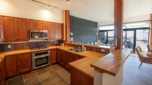 A modern kitchen with wooden cabinets, stainless steel appliances, and a large island. - Big Beach Escape – Oceanview•Walk to Trail•Fireplace (Ucluelet)
