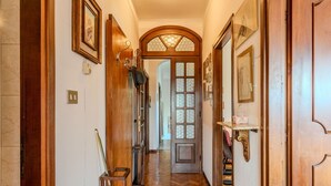 Un couloir en bois doté d’un parquet en chevrons, d’une porte en bois avec des panneaux de verre et d’un porte-manteau fixé au mur.