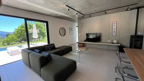 A modern living room with a sofa, a glass coffee table, a flat-screen TV, and a fireplace. - Sensation Ventoux, villa in Baronnies provençales (Beauvoisin)