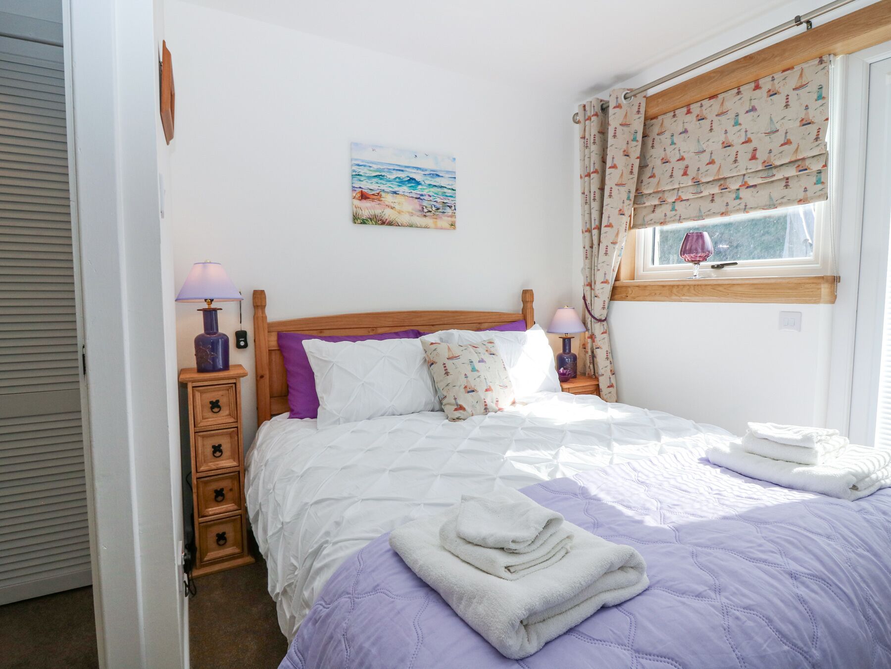 Una camera da letto con un letto di legno, un comodino con una lampada, una finestra con tende e un quadro appeso al muro.