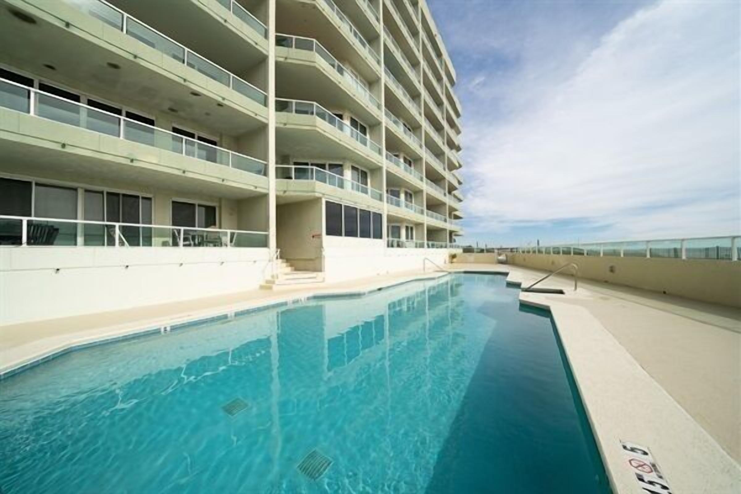Una piscina junto a un edificio de varios pisos con balcones.