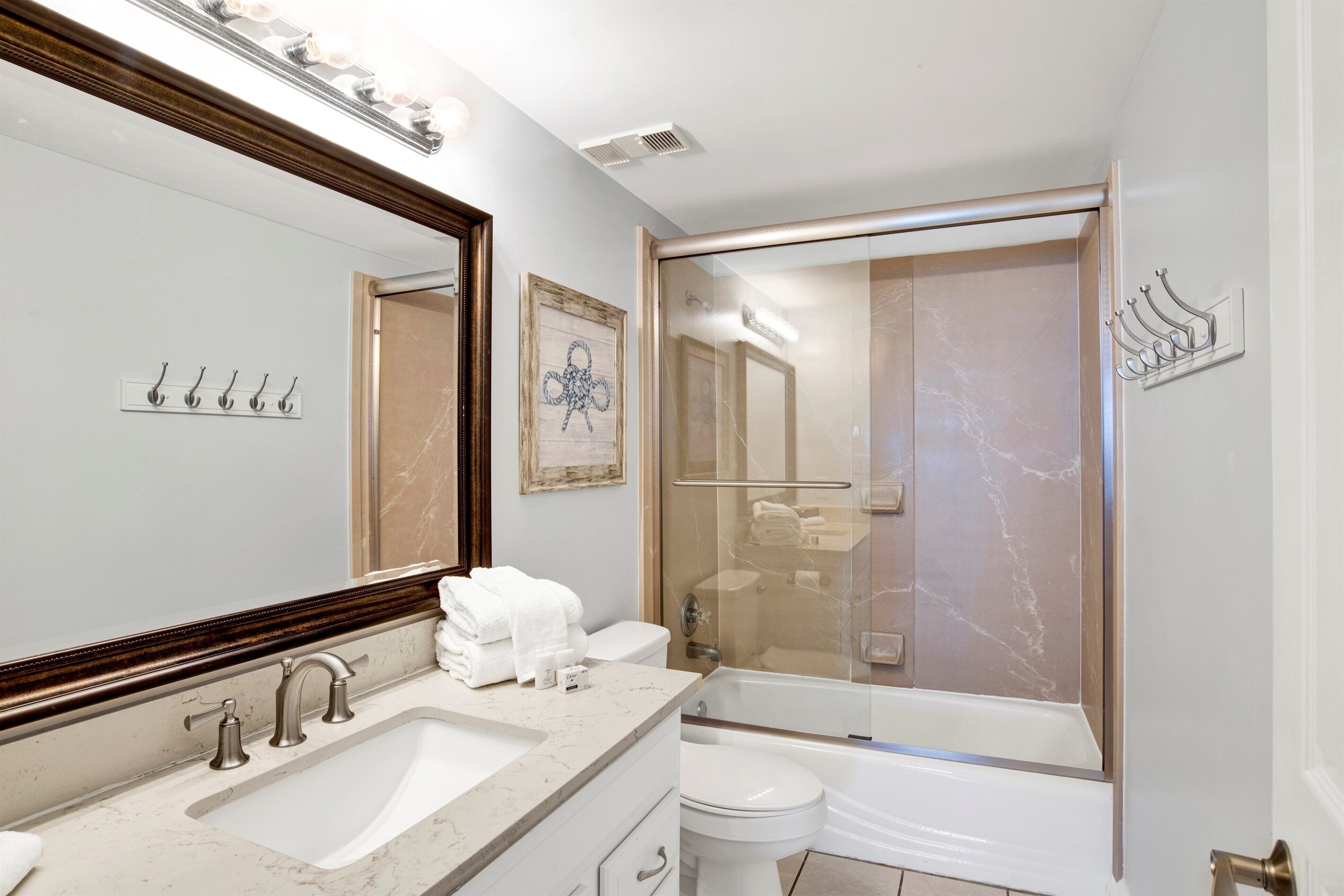 Une salle de bain moderne avec un grand miroir, un lavabo, des toilettes et une douche à parois de verre.