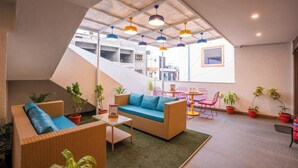 Una terrazza panoramica con mobili in vimini, piante in vaso e luci pendenti colorate.