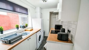 A compact kitchen with a washing machine, a microwave, and a toaster. - Comfortable house in Hartlepool (Hartlepool)