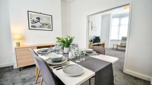 A dining area with a table set for four, a plant, and a framed artwork on the wall. - Comfortable house in Hartlepool (Hartlepool)