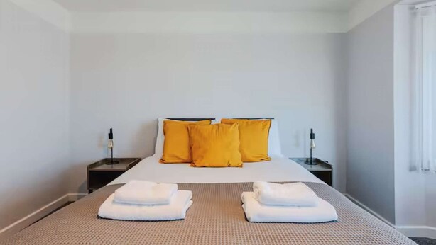 Ein Hotelzimmer mit einem Bett, zwei Nachttischen und zwei Handtüchern auf dem Bett.