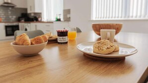 Ein Frühstückstisch mit Croissants, einer Schale Kekse, einer Tasse und einem Glas Orangensaft.