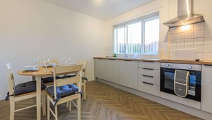 A compact kitchen with a dining area, featuring a window, a built-in oven, and a modern stove. - Comfy house in Thornaby, Stockton On Tees (Thornaby on Tees)