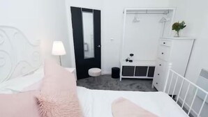 Une chambre à coucher avec un lit, une commode, un miroir et un petit tabouret.