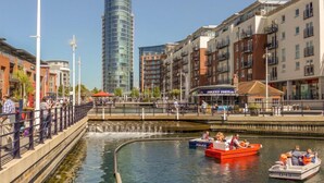 Un canal avec des bateaux, un bateau de police et, au fond, un grand immeuble moderne.