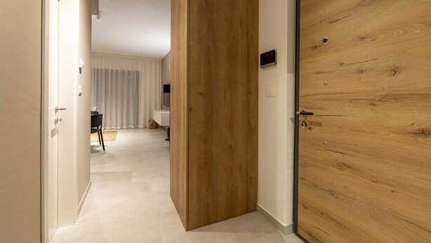 A hallway with a wooden door and a white wall. - Apartment Tissa (Pula)