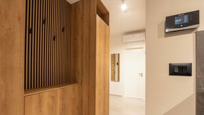 A modern interior with a wooden panel wall, a digital thermostat, and a tiled floor. - Apartment Tissa (Pula)