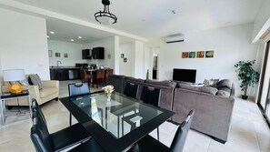 A modern living room with a glass-top dining table, a sofa, and a TV. - Jaco Bay 5701 (Jaco Beach)
