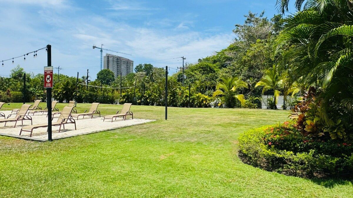 A grassy outdoor area with lounge chairs and a signpost.