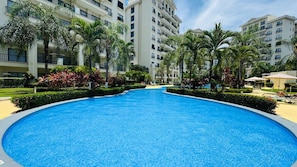 A swimming pool surrounded by palm trees and a multi-story building. - Jaco Bay 5701 (Jaco Beach)