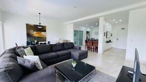 A modern living room with a sectional sofa, a coffee table with a plant, and a dining area with chairs and a table. - Jaco Bay 5701 (Jaco Beach)