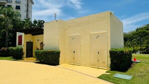 A building with two doors, a covered entrance, and a paved area with grass and bushes. - Jaco Bay 5701 (Jaco Beach)
