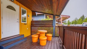 Una terraza de madera con una puerta amarilla y una pequeña mesa con cuatro taburetes.