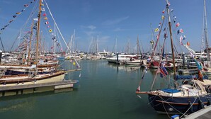 Un port de plaisance où de nombreux bateaux sont amarrés, avec une variété de drapeaux et de mâts.