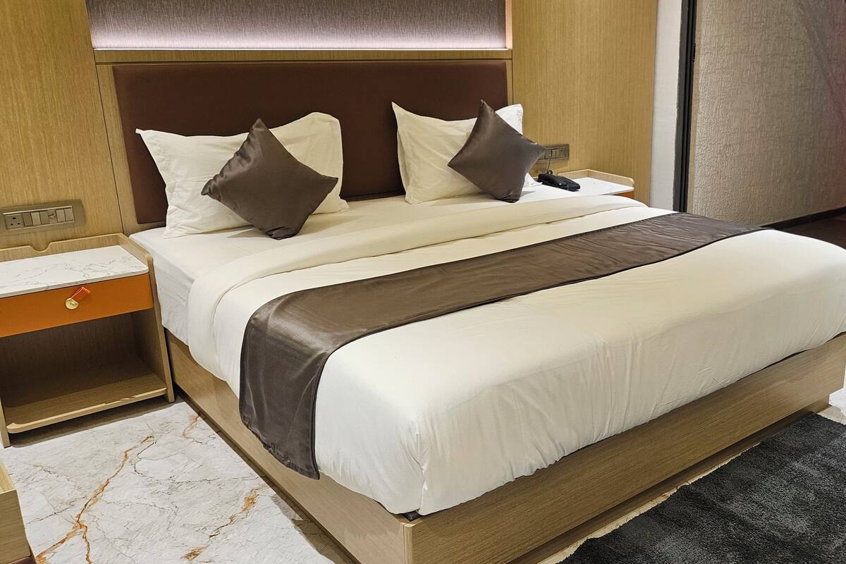 Hotellihuone, jossa on suuri sänky, yöpöytä, marmorikuvioitu lattia ja näkymä ulos.