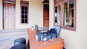 Ein Empfangsschalter mit Drucker, Laptop und einer kleinen Pflanze. Zwei Holztüren und ein Fenster mit Blick.