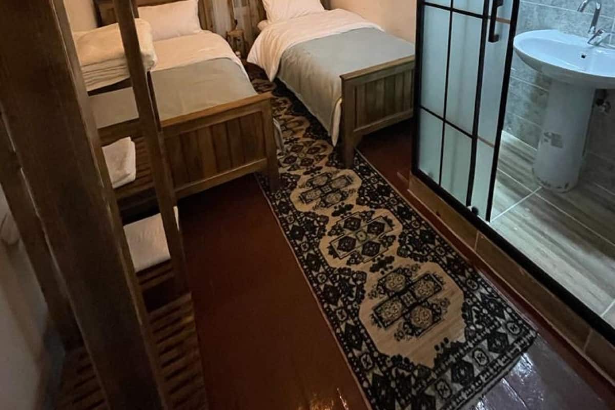 Une chambre avec deux lits, un grand miroir et une salle de bain avec un lavabo.