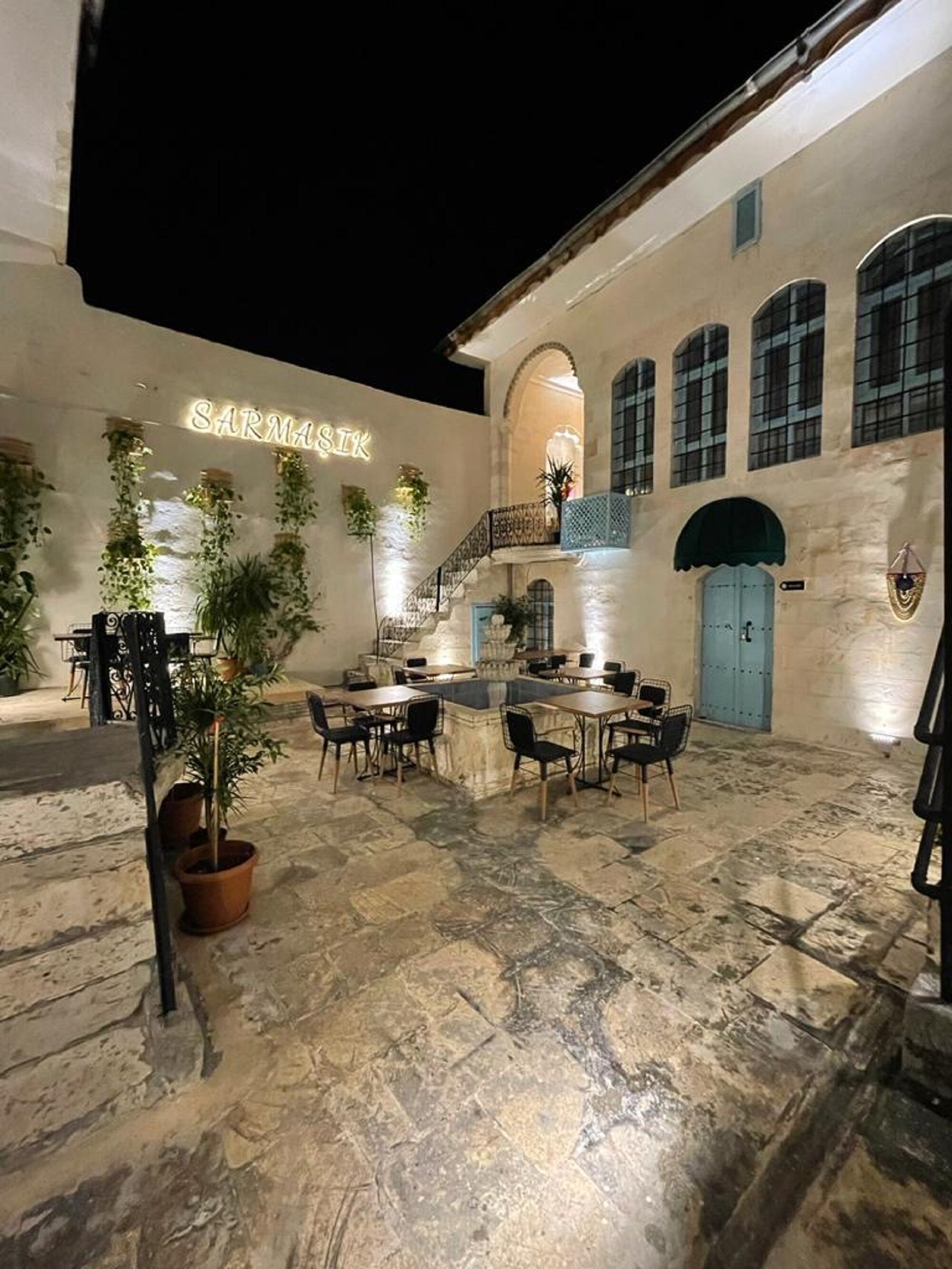 Un patio con suelo de piedra, mobiliario exterior y plantas en macetas.