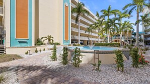 Un hotel con piscina, palmeras y un camino de ladrillo.