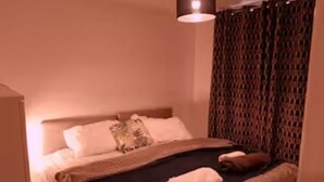 A bedroom with a bed, pillows, a blanket, and a hanging light fixture.