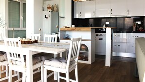 A modern kitchen with white cabinetry, a wooden countertop, and a dining area with white chairs and a table. - Incredible first line Levante beach Salou (Salou)