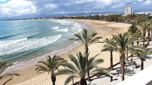 A beach with palm trees, a sandy shore, and a view of the ocean. - Incredible first line Levante beach Salou (Salou)