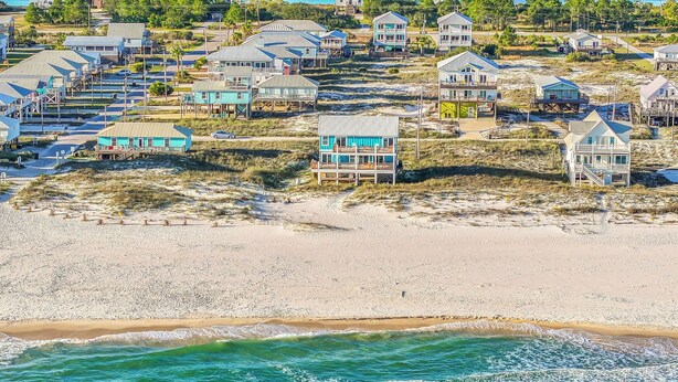 A coastal area with beachfront houses, some with balconies, and a sandy beach. - Dog-Friendly Beachfront Home with Pool (Gulf Shores)