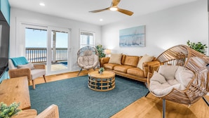 A modern living room with a sofa, chairs, a round coffee table, and a ceiling fan. - Dog-Friendly Beachfront Home with Pool (Gulf Shores)