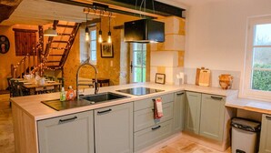 A kitchen with a central island, a built-in stove, and a window overlooking greenery.