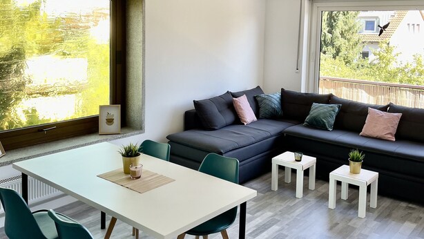 A modern living room with a sofa, a dining table, and chairs. There is a window with a view of the outside. - Apartment with balcony, Stein near Nuremberg (Stein)