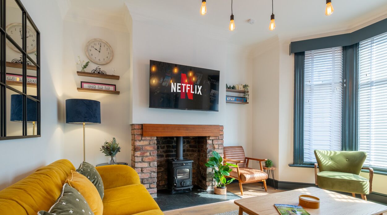 Een woonkamer met een open haard, een aan de muur bevestigde televisie en een bank.